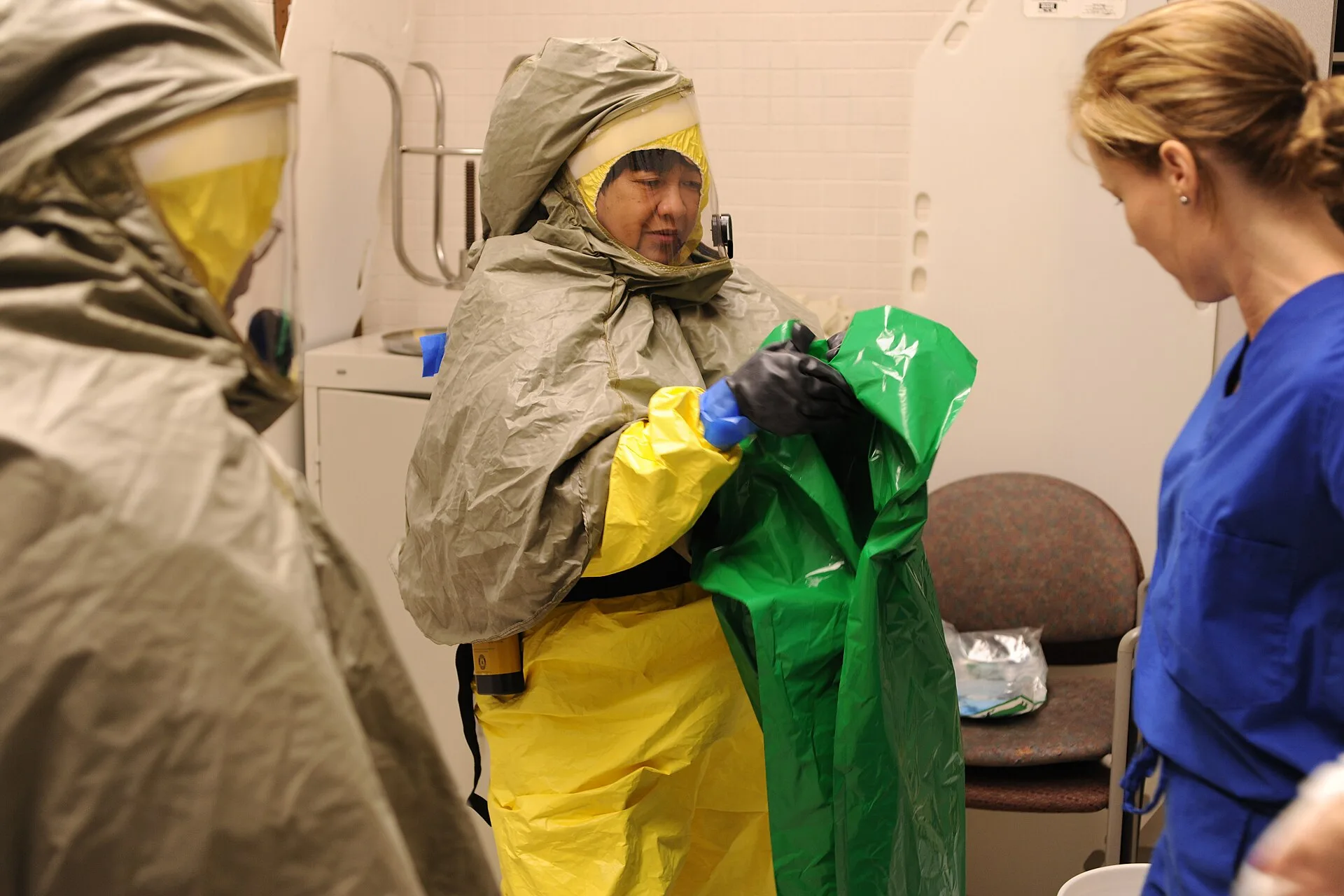 Responder in a yellow and green chemical-protective hazmat suit during decontamination