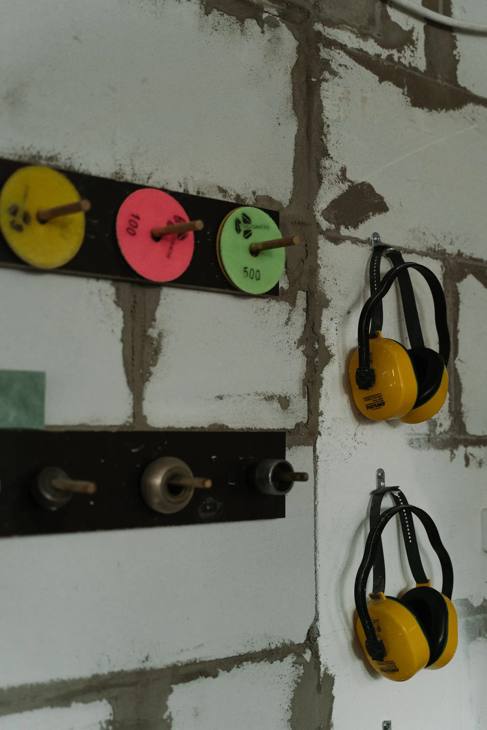Two yellow earmuffs hanging on a workshop wall
