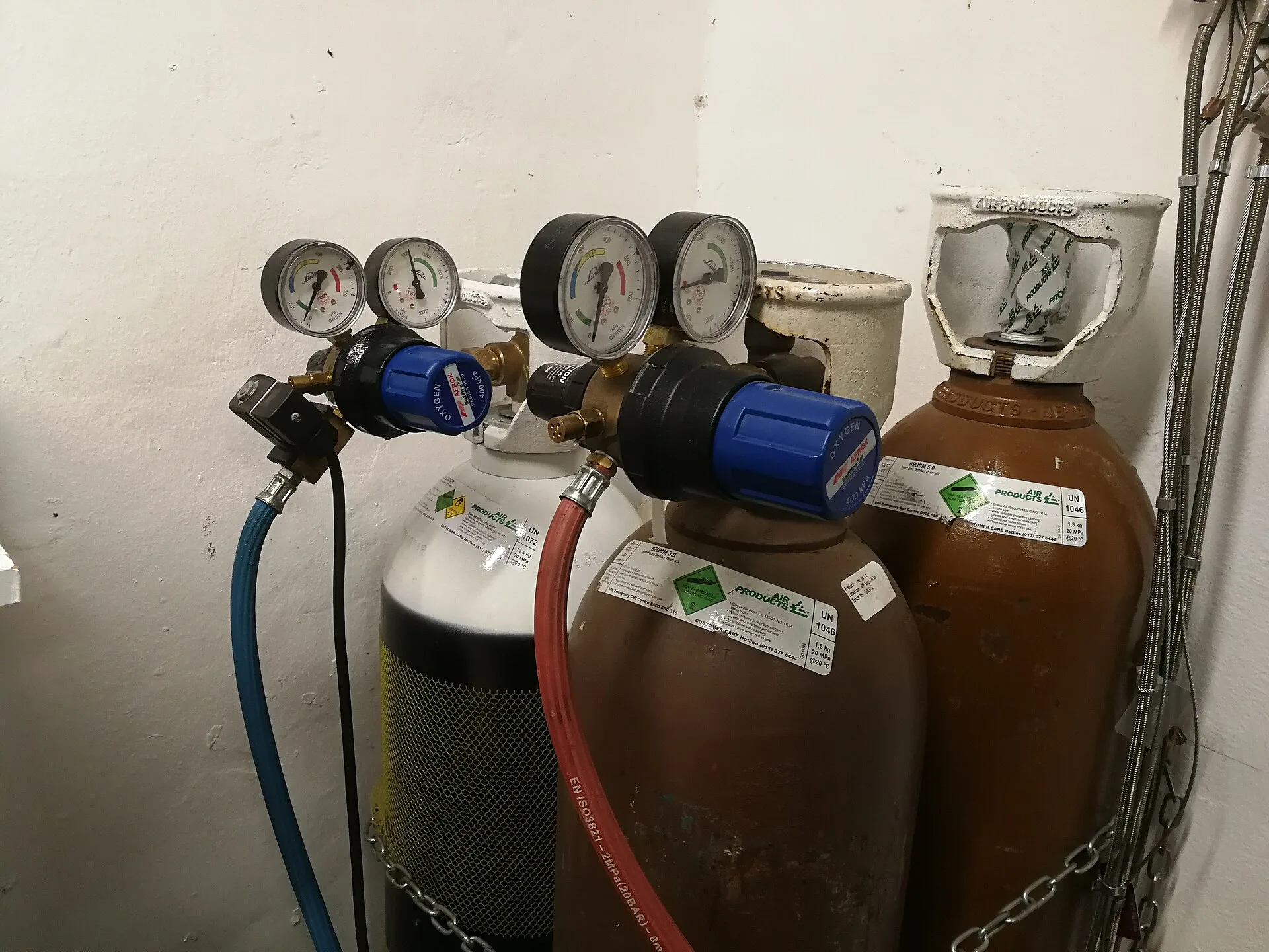 Pressure regulators with gauges fitted to chained gas cylinders supplying controlled gas flow