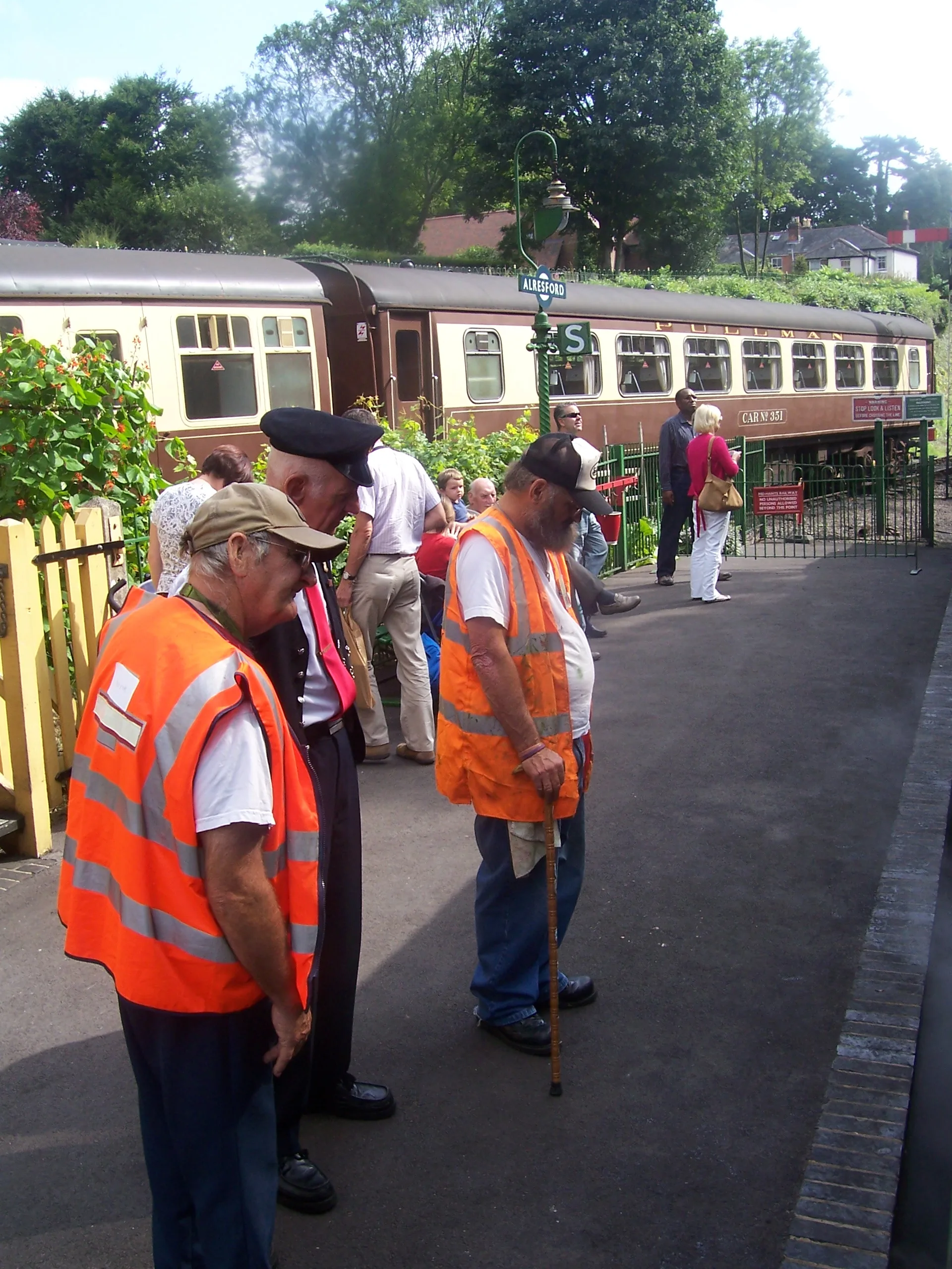 Railway volunteers wearing orange high-visibility vests on a station platform