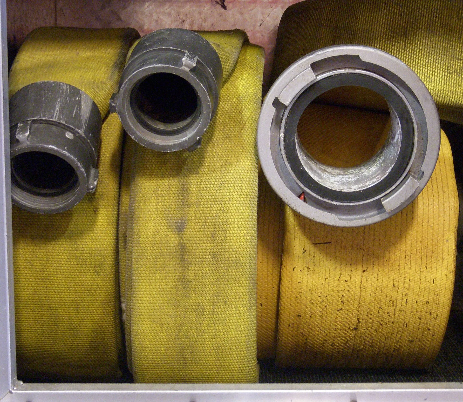 Rolled yellow lay-flat fire hoses with aluminium Storz couplings