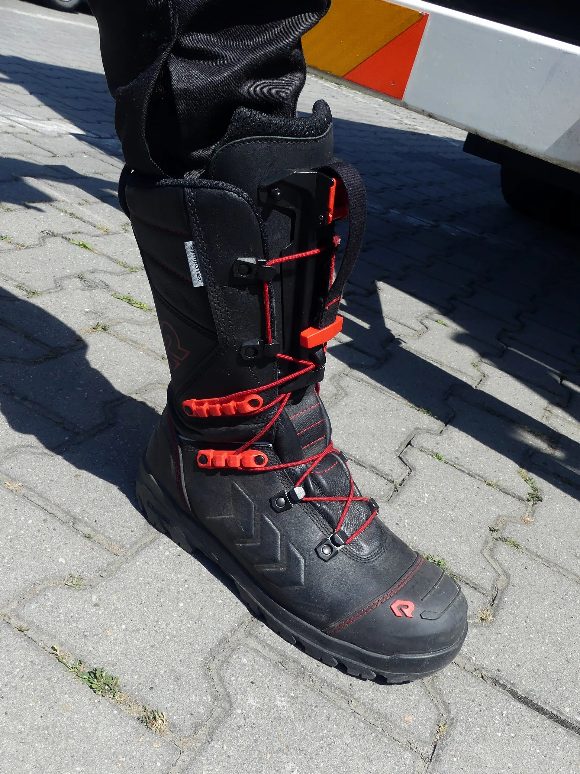 Black modern firefighting boot with quick-lace system worn with protective trousers