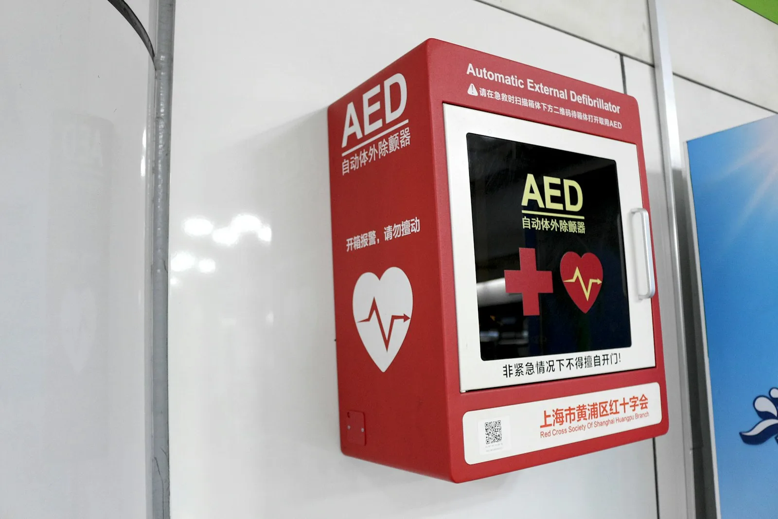 Red wall-mounted automated external defibrillator (AED) cabinet with glass window