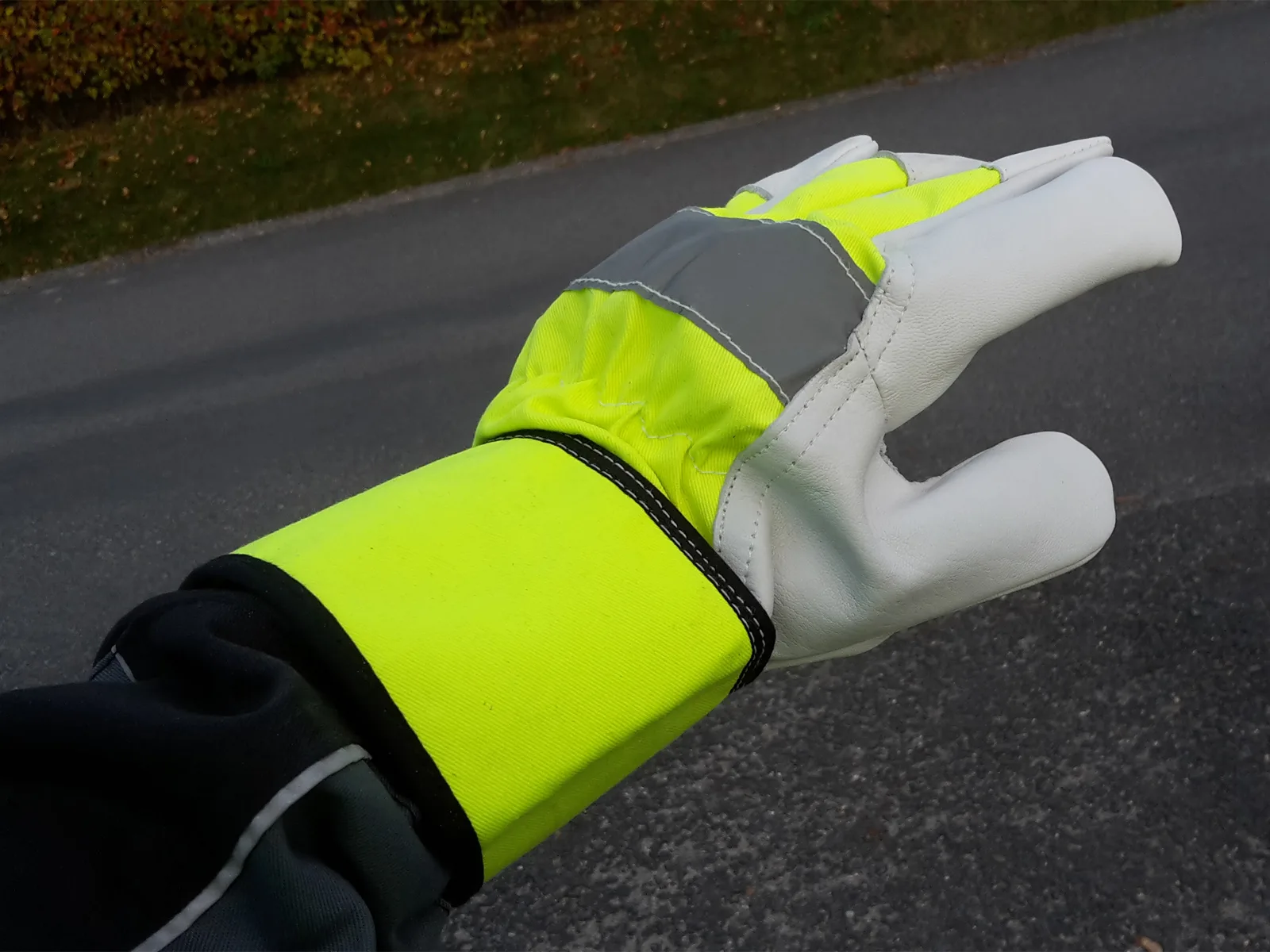 Grain-leather work glove with fluorescent yellow reflective cuff worn outdoors
