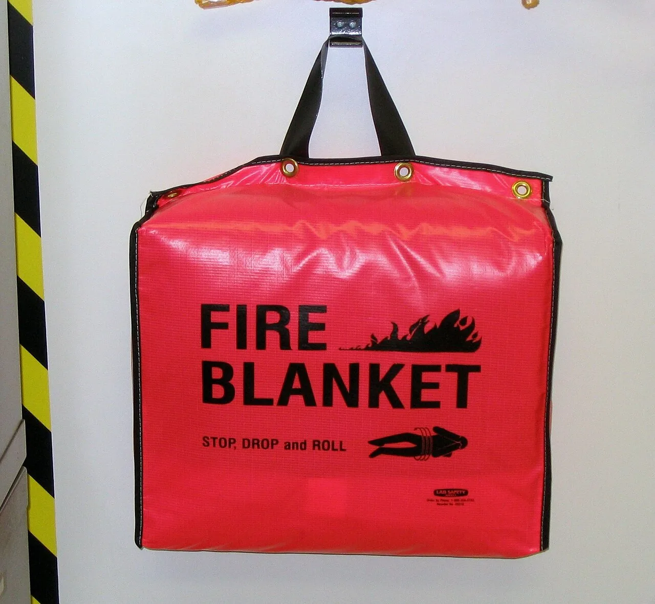 Red wall-hung fire blanket pouch printed FIRE BLANKET with stop, drop and roll pictogram