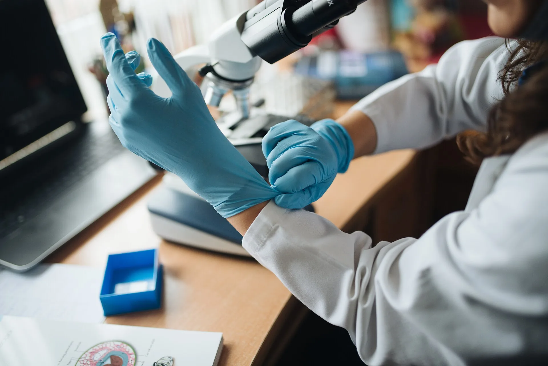 Laboratory technician pulling on blue disposable nitrile gloves
