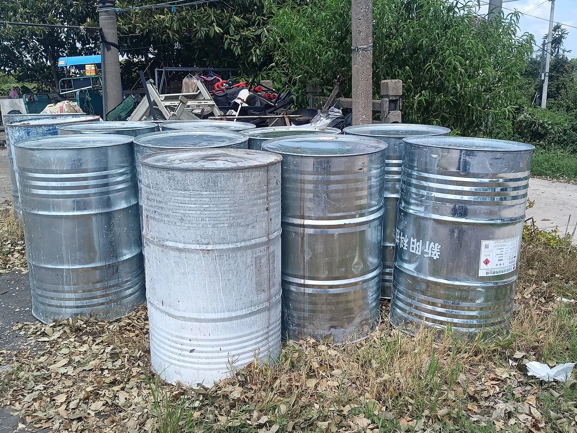 Group of galvanised steel chemical drums stored outdoors