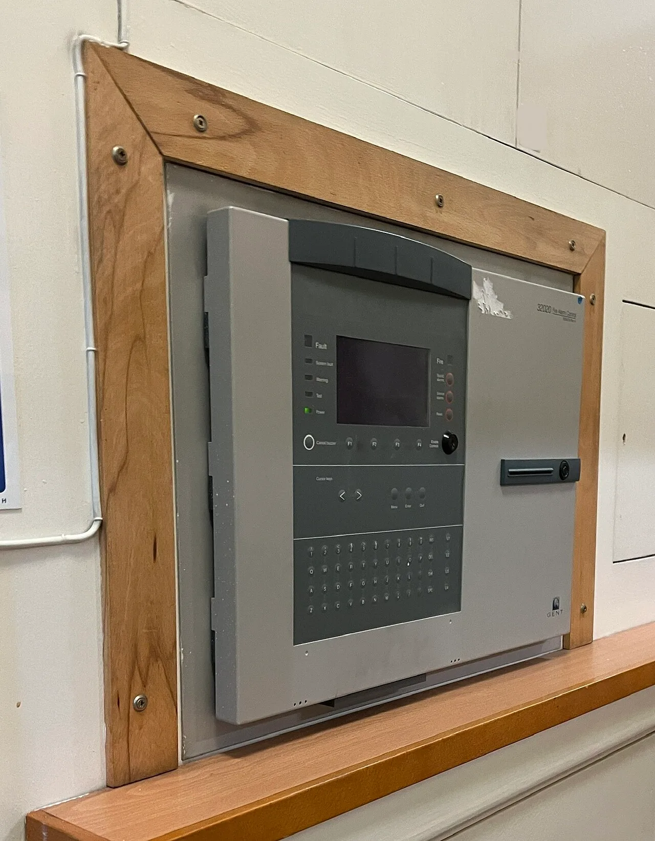 Grey addressable fire alarm control panel with LCD display and keypad mounted on a wall