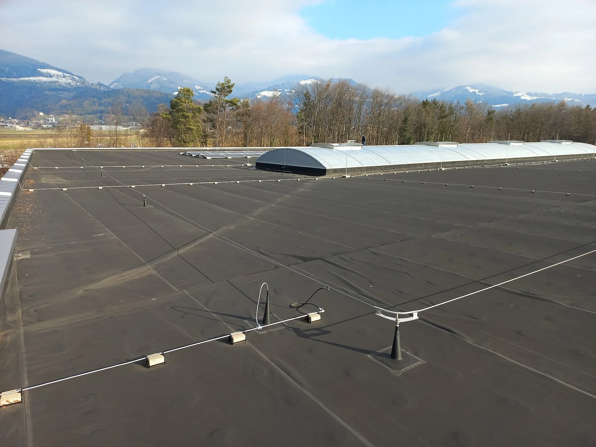 Flat roof fitted with post anchors and a horizontal steel-cable lifeline system