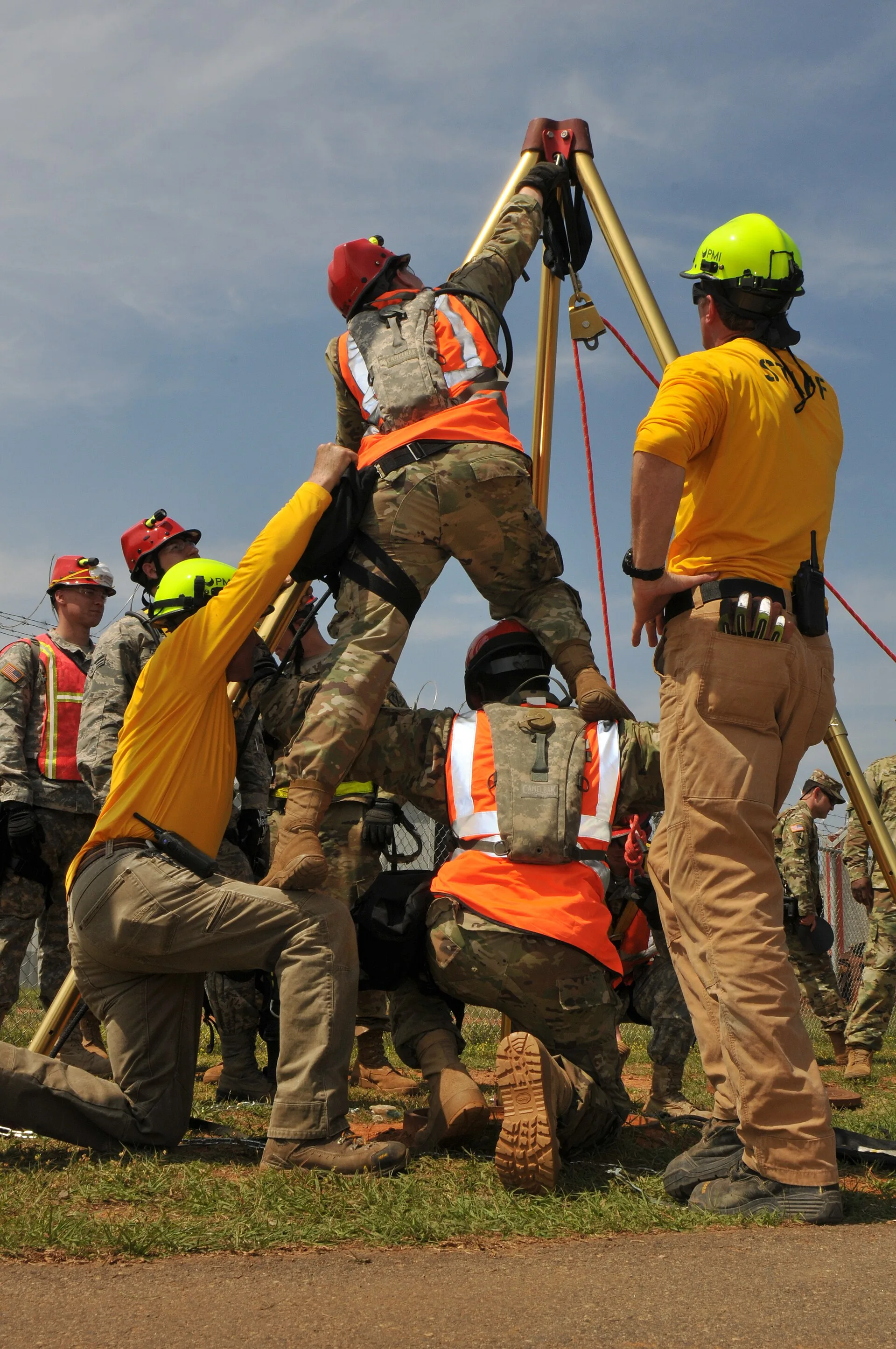 Rescue team lowering a harnessed worker through a confined-space tripod