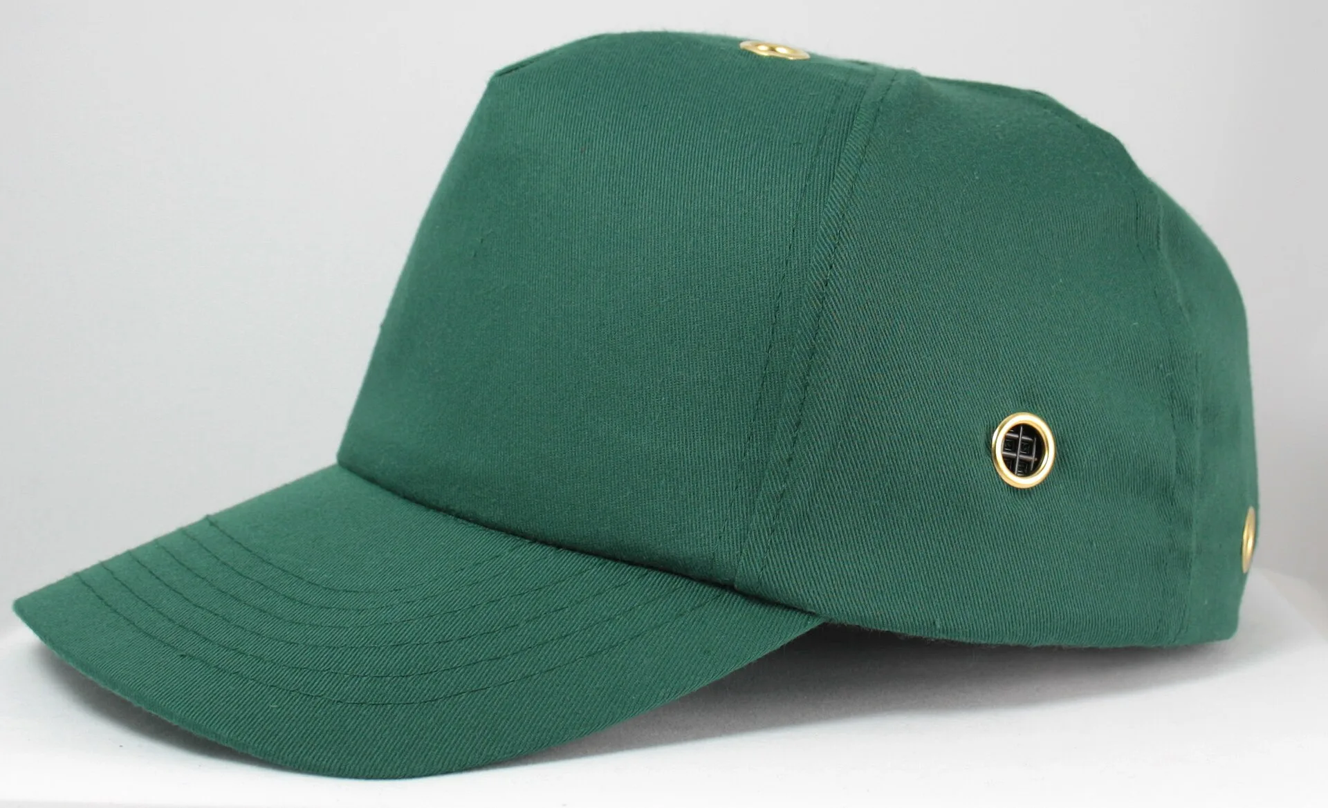 Green baseball-style bump cap with ventilation eyelet on a white background