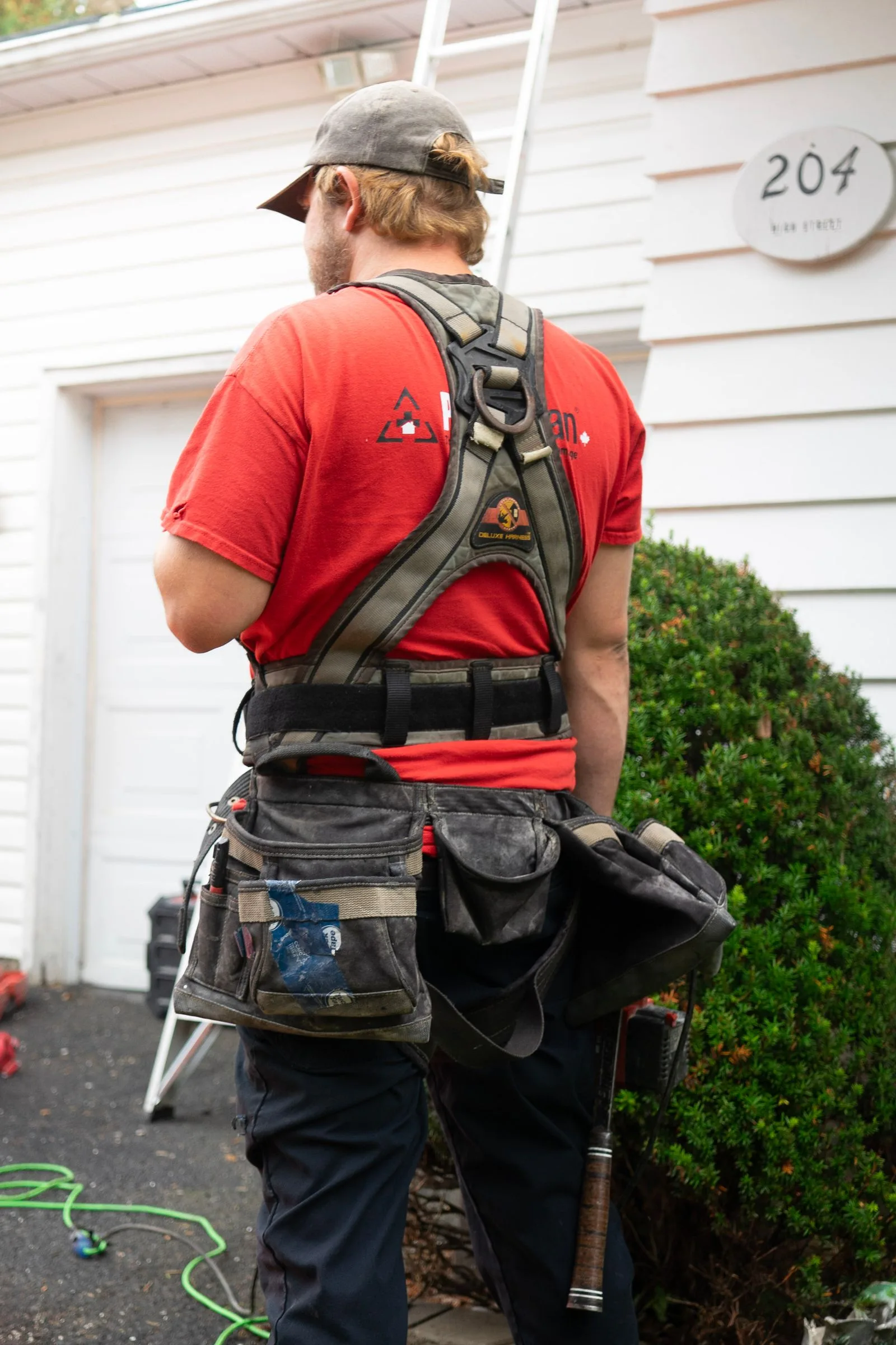 Rear view of a worker wearing a full-body harness and tool belt