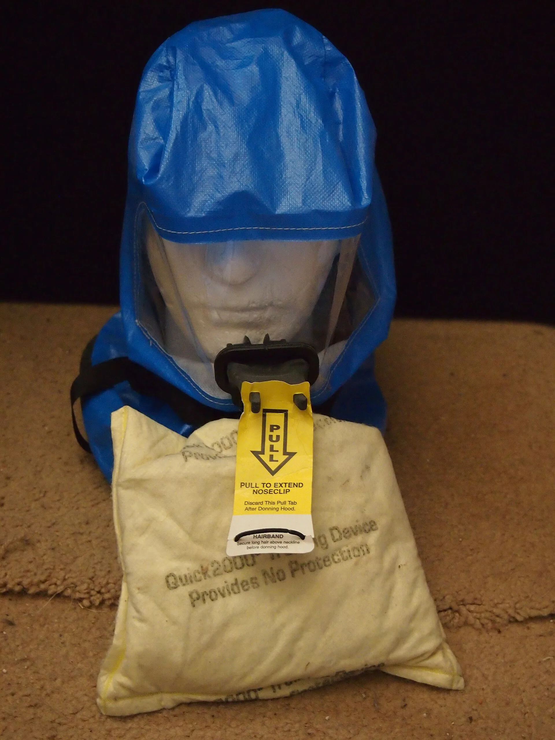 Blue emergency escape smoke hood with filter displayed on a mannequin head above its pouch